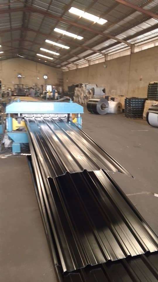 Long roofing sheets running through a forming machine in a workshop